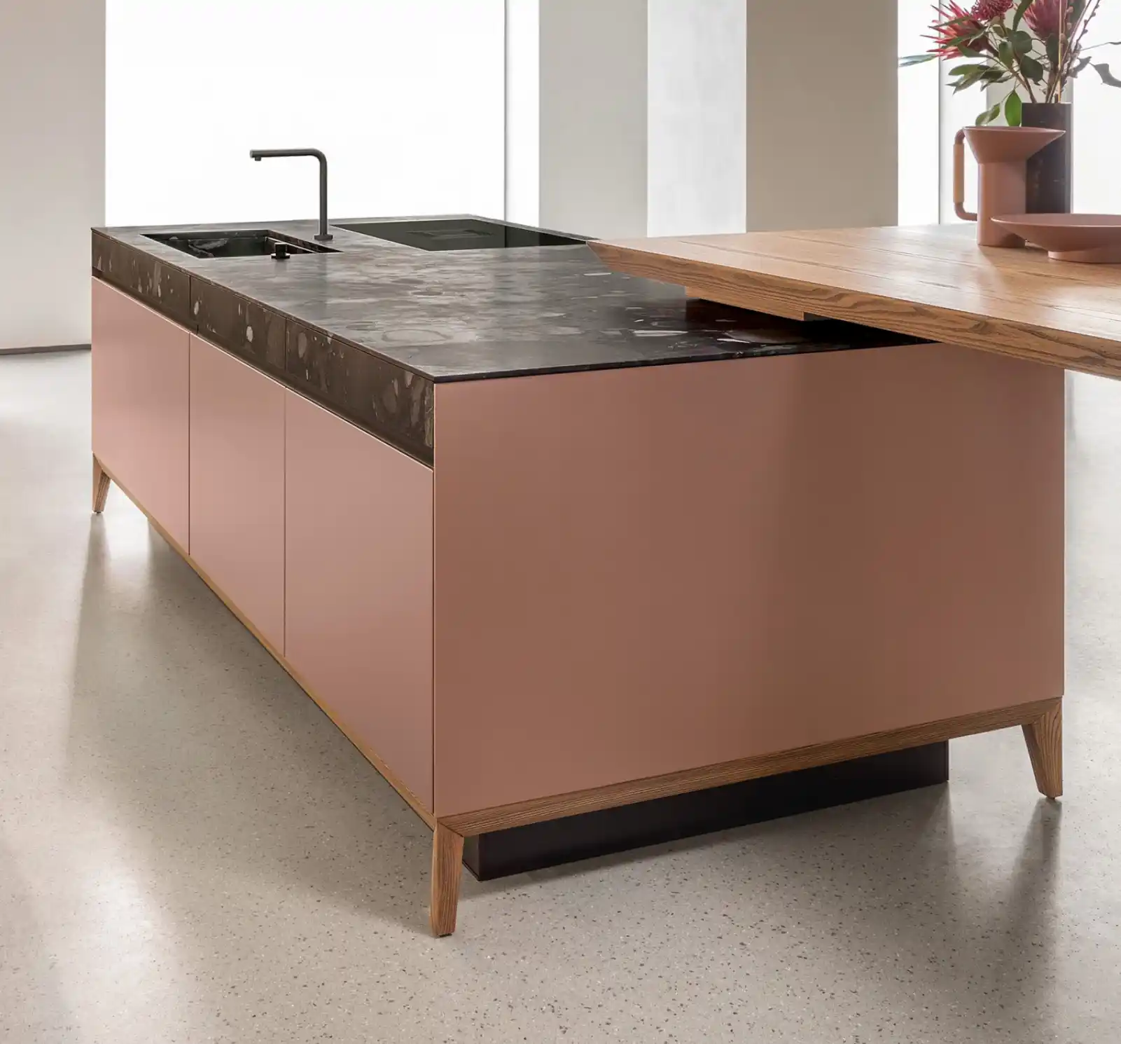 Îlot de cuisine contemporain avec mobilier rose mat, plan en pierre sombre et table en bois naturel