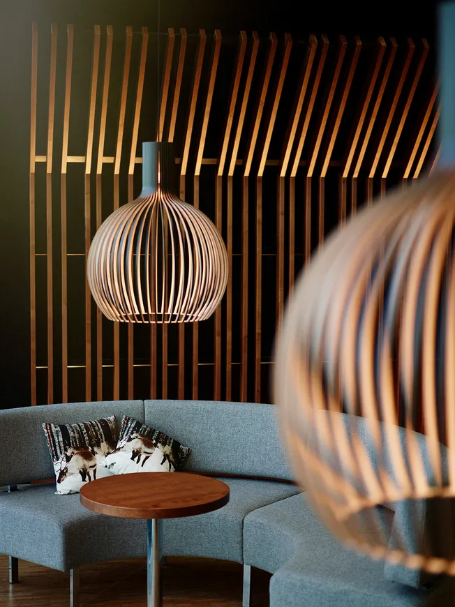 Canapé gris courbe avec luminaires en bois et mur à lattes